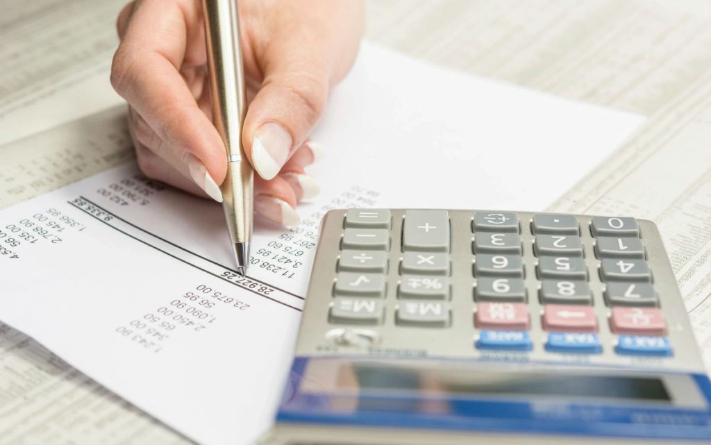 Hand marking figures beside calculator