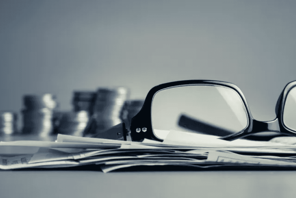 Reading glasses on financial documents and coins